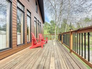 a deck with two red chairs on a house at Vacances Magiques Chalet Skadi Paix Nature in Saint-Justin +23 photos