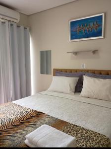 a bedroom with a large bed with a picture on the wall at Hotel Pousada Villa Monnaié centro in Chapada dos Guimarães