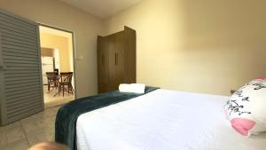 a bedroom with a white bed and a table at Casa Aconchegante Sete Lagoas - 35A in Sete Lagoas