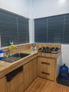 a kitchen with wooden cabinets and a sink and windows at Nature Retreat Mantayupan Waterfalls in Barili