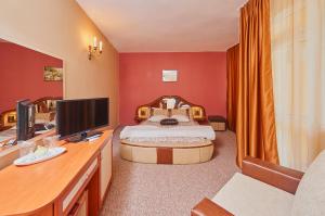 a bedroom with a bed and a desk with a television at Peneka Hotel in Pomorie