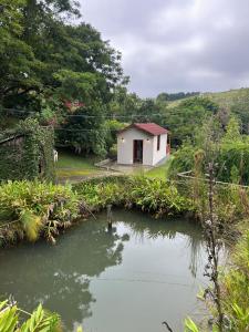 a small white building next to a body of water at Centro de Lazer Pingo d'água in Caxambu