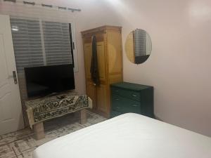 a bedroom with a bed and a dresser and a television at dakhla extreme in Oulad Akkou +2 photos