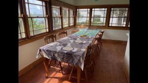 a dining room with a table and some windows at Cliff Cottage - Noraville in Norah Head