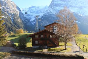 a house in front of a mountain with a ski lift at Superior Apartment 100m2 Bodmisonne - Grindelwald in Grindelwald