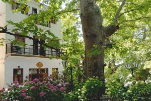 a tree and flowers in front of a building at Gastronomy Hotel Kritsa in Portaria