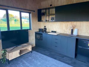 a kitchen with blue cabinets and a flat screen tv at Flora Farmstay in Makarewa