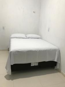 a white bed with two pillows in a white room at Vila Aconchego in Bragança