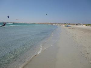 an empty beach with a person in the water at Limnos Stone House in Kalliópi