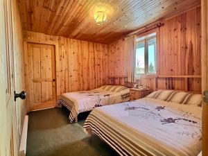 two beds in a room with wooden walls at Domaine Appalaches 30 Incredible view in Saint-Paul-de-Montminy +39 photos