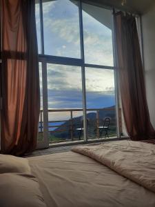 a bedroom with a bed and a large window at Penginapan Homestay Sikunir - Bukit Bintang Dusun Musilan in Kejajar