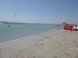 a beach with people in the water and a kite at Limnos Stone House in Kalliópi