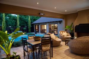 un patio con mesa, sillas y piscina en Rise and Shine Lodge, en Bloemfontein