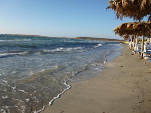 a beach with umbrellas and chairs and the ocean at Limnos Stone House in Kalliópi