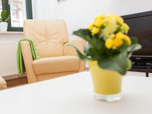 a vase of yellow flowers on a table with a chair at Ferienwohnung Leipzig Ost in Leipzig