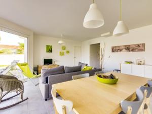 un soggiorno con un tavolo e un divano di Maison contemporaine Biscarrosse, 7 pers., 3 ch., Wi-Fi, sur terrain 700m², proche activités et plages - FR-1-521-44 a Biscarrosse
