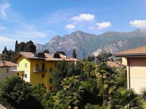 a yellow apartment building with mountains in the background at Casa Vacanze Claudette in Arco