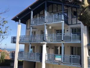 a building with white balconies and the ocean in the background at Appartement avec Terrasse et Piscine à Guéthary, Proche Plages - FR-1-239-604 in Guéthary