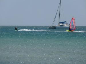a person on a surfboard in the ocean with a sailboat at Limnos Stone House in Kalliópi