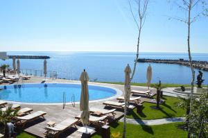 a pool with chairs and umbrellas next to the ocean at Carmen International Hotel Venus - Fost Becali Hotel in Venus