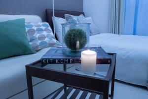 a candle on a glass table next to a bed at Home Tokyo Takinogawa in Tokyo