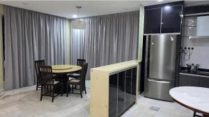 a kitchen with a table with chairs and a refrigerator at Kuantan Tok Sira Spacious 5 Rooms Bangalow near Teluk Cempedak in Kuantan
