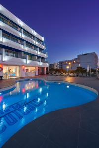 a swimming pool in front of a building at night at Marina Playa Hotel Apartments by Typic Hotels - Adults Only in San Antonio Bay