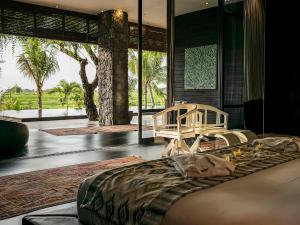 a bedroom with a large bed and a room with palm trees at Villa Mana by Elite Havens in Canggu