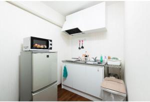a small kitchen with a refrigerator and a microwave at 花迹民宿一号馆201 通天阁天王寺步行圈 心斋桥日本桥4分钟车程 in Osaka