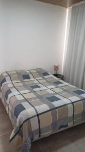 a bed in a room with a plaid blanket on it at Las Piedras in Pilar +11 photos