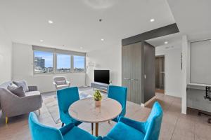 Una sala de estar con sillas azules y una mesa. en Trafalgar Lane Apartments by CLLIX, en Brisbane 38 fotos más