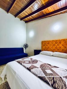 a bedroom with a bed and a blue couch at CASA FAMILAR frente al parque in Buga