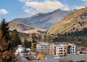 a building in a city with mountains in the background at Modern Luxury Condo Shotover Views in Queenstown
