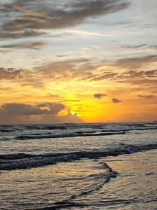 a sunset over the ocean with waves at Dunas House in Luis Correia