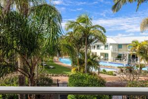 a view of a resort with a pool and palm trees at Oaks Pacific Blue Port Stephens. Apartment overlooking the Pool in Salamander Bay