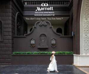 a woman walking down a street in front of a building at Marriott Executive Apartments Bangkok, Sukhumvit 101 in Bangkok