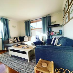 a living room with a blue couch and a coffee table at Spindrift Falmouth, adventurers coastal haven in Falmouth