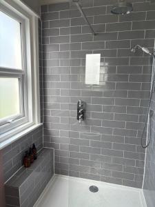 ein Bad mit einer grau gefliesten Dusche und einem Fenster in der Unterkunft Pretty period property sleeps 4 guests with shared garden in Worthing + 17 Fotos