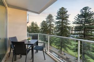 balcón con mesa, sillas y árboles en Belle Escapes - Coast on Colley Terrace, en Glenelg