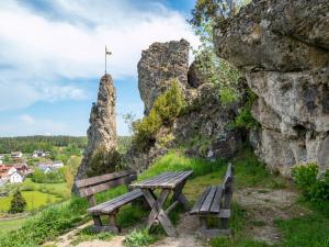 two wooden benches sitting on a hill with rocks at Ferienhaus Holunderweg an der Theme Obernsees mit Sauna in Truppach