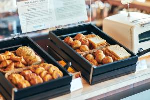 two trays of different types of bread and pastries on a counter at Park Hotel Tokyo in Tokyo