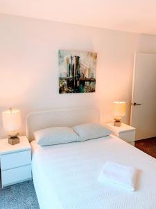 Un dormitorio con una cama blanca y dos lámparas. en Western Lemon Grove, en Los Ángeles