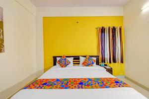 a bedroom with a bed with a yellow wall at FabHotel Namaha Suites - Nr Hyderabad International Airport, Shamshabad in Hyderabad +27 photos