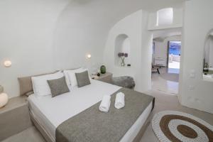 a white bedroom with a large bed and a living room at Kyrkos Collection in Fira