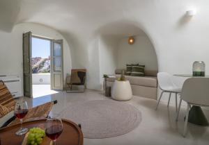 a living room with a couch and a table with wine glasses at Kyrkos Collection in Fira