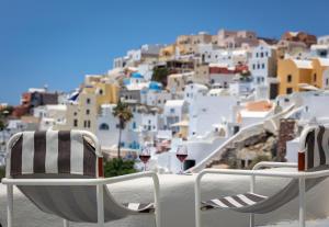 a table with two glasses of wine and a view of a city at Kyrkos Collection in Fira
