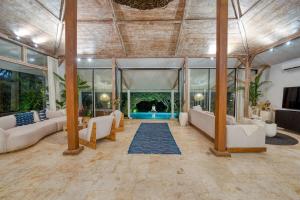 an open living room with white furniture and large windows at Villa Sosso 5BR Brand New Villa in Pererenan in Dalung