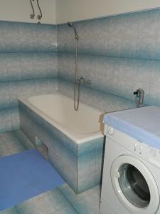 a bathroom with a tub and a washing machine at Bartulovi dvori in Poljica