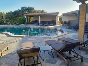 a swimming pool with chairs and a table next to it at Le Devem De Mirapier in Cornillon-Confoux