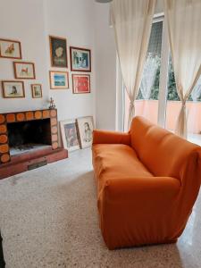an orange couch in a living room with a fireplace at Le Giramondo Appartamento Le Cavallerizze in Caserta
